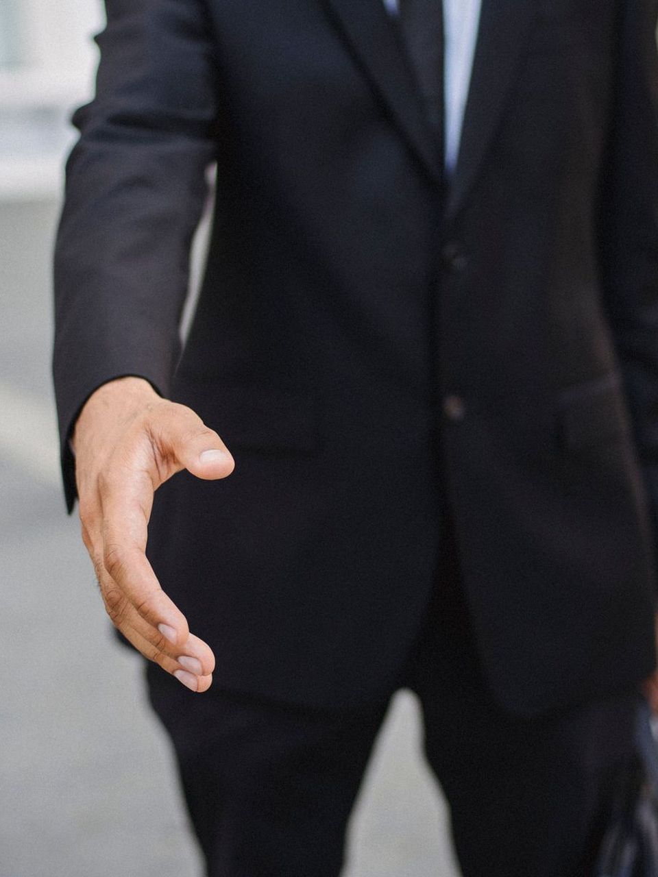 Profissional de fato estende a mão para cumprimentar quem chega