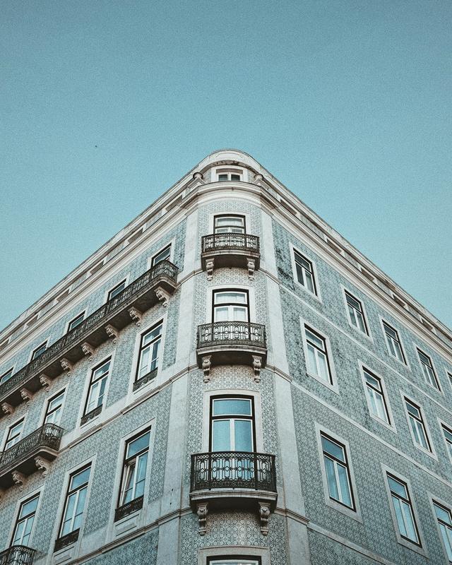 Fachada de um prédio de habitação em Lisboa, revestida a azulejo, com varandas de ferro